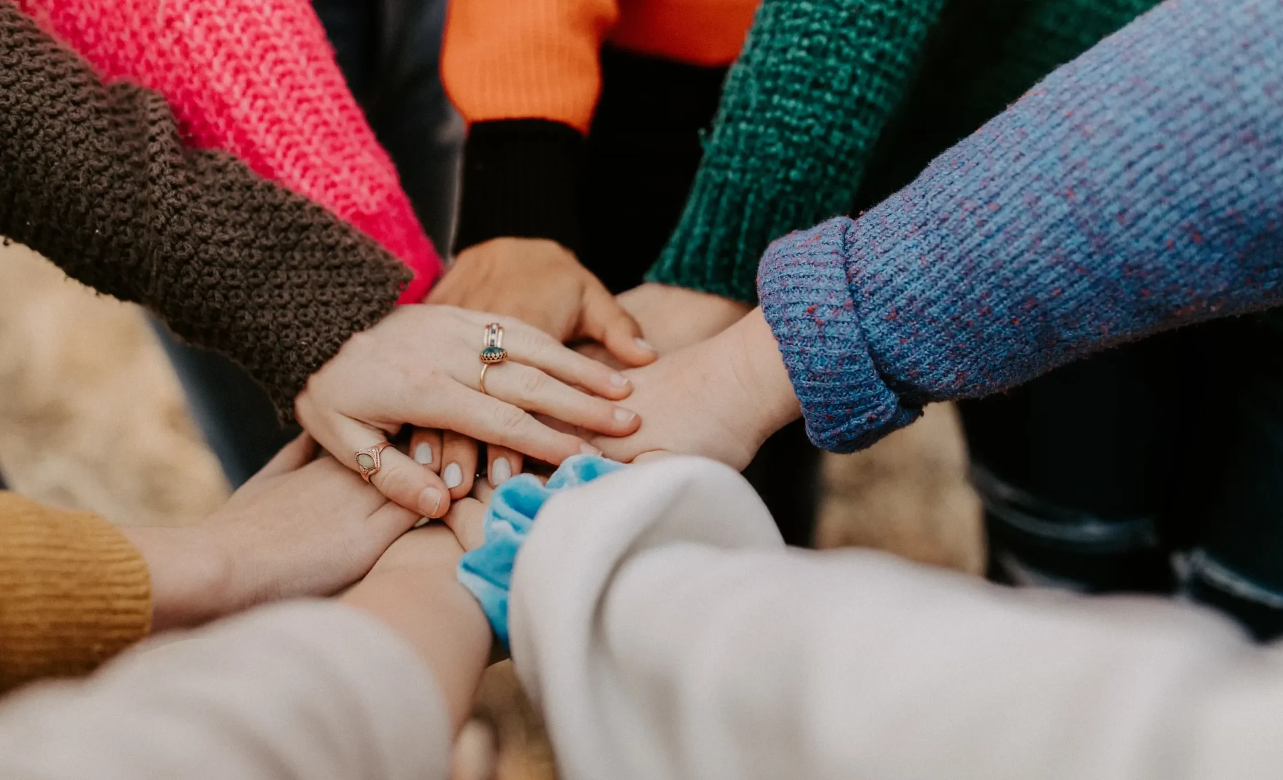 Closeup shot of people joining their hands together in a huddle