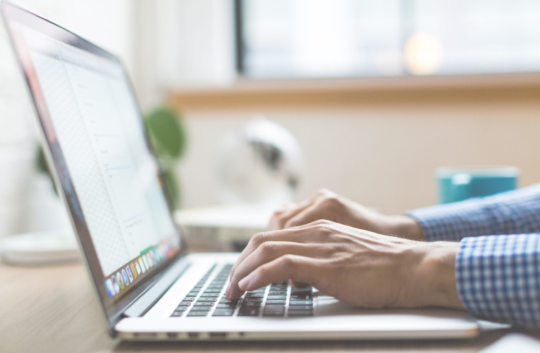 Closeup of an individual's hands typing on a laptop keyboard