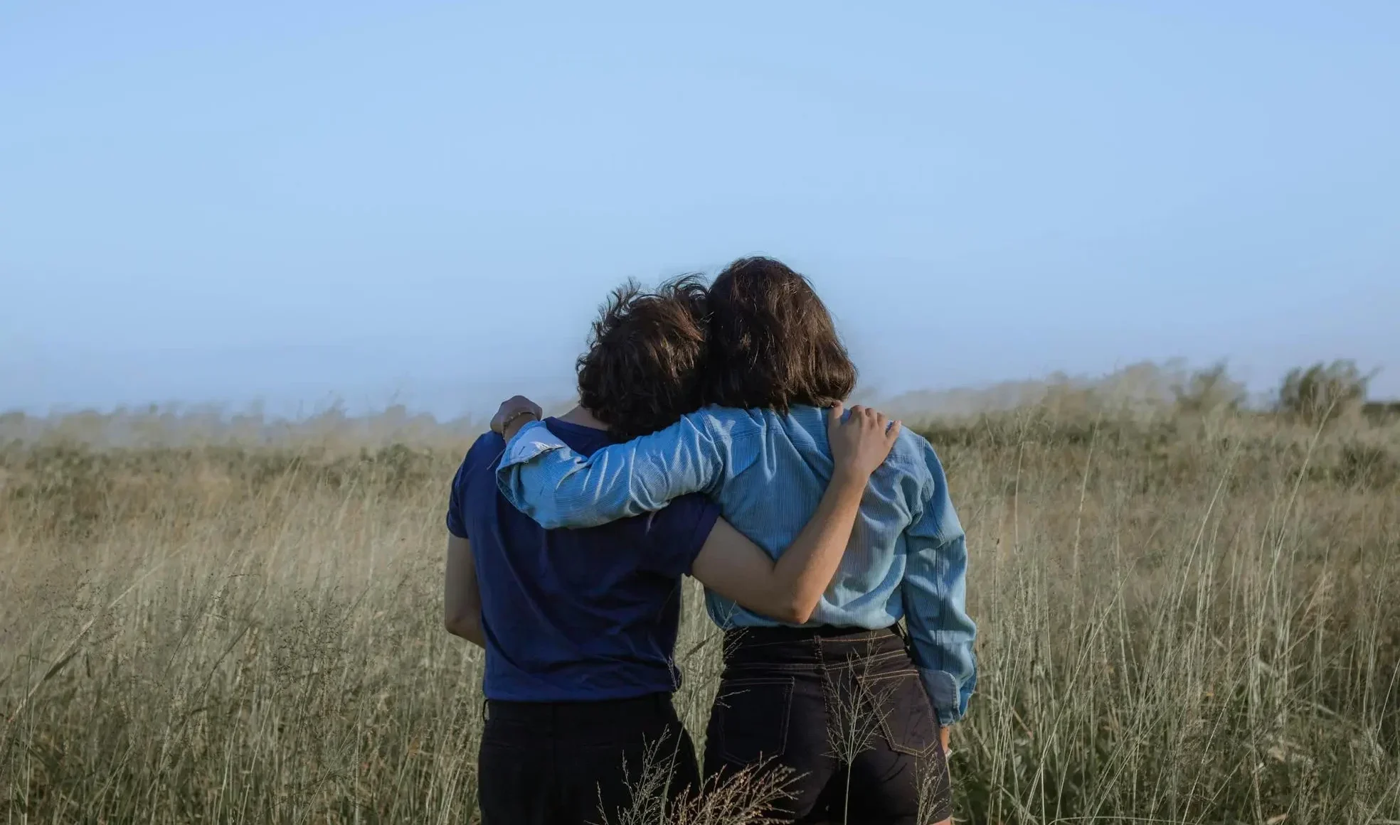 An image of two individuals embracing in a field