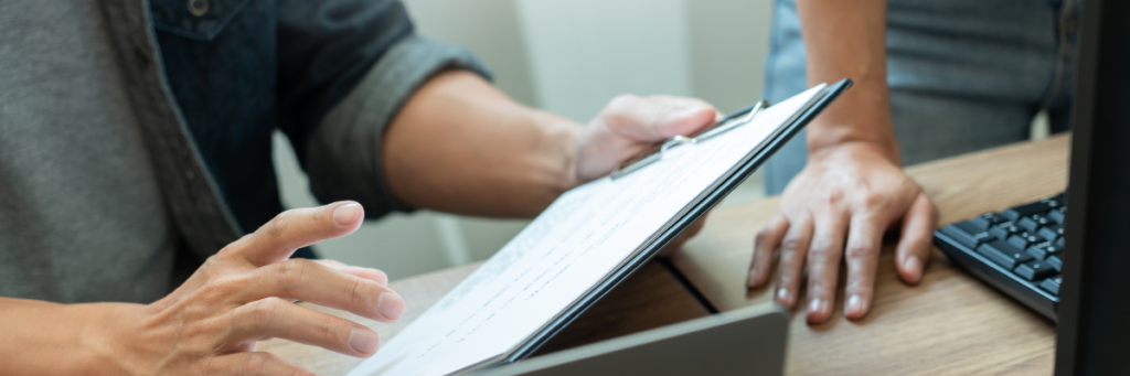 Close up of two individuals' hands holding a clipboard